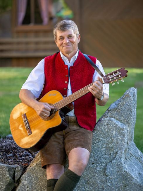 Bäff mit Gitarre sitzend auf einem Stein