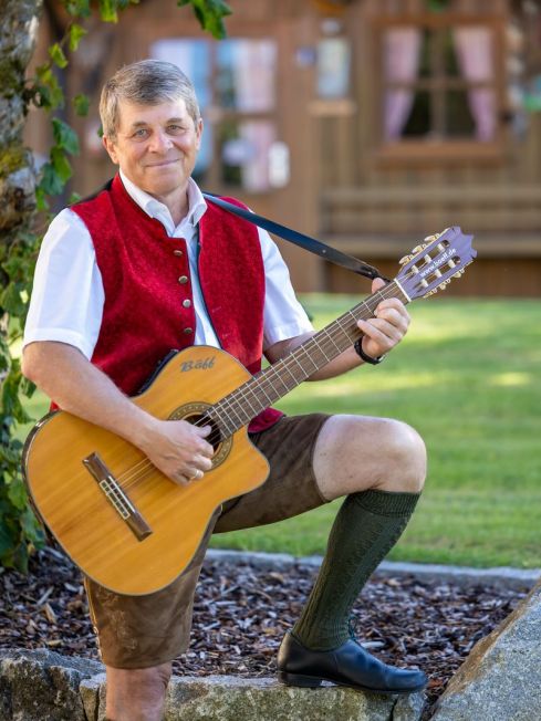 Bäff mit Gitarre stützend auf einem Stein