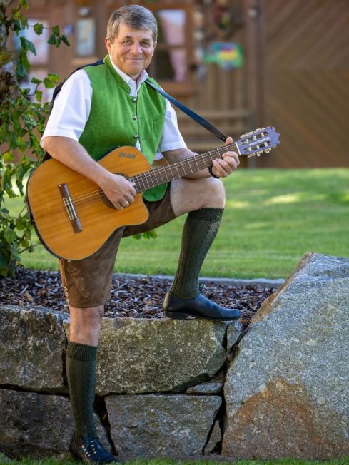Bäff mit Gitarre stützend auf einem Stein