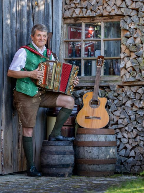 Bäff mit Harmonika stehend auf einem Holzfass