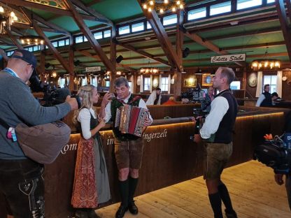 Bäff in Tracht mit der Harmonika vor dem Kamerateam
