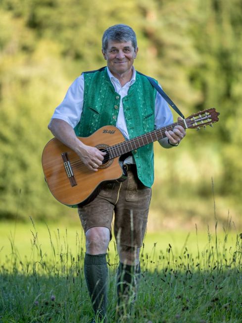 Bäff schreitet mit Gitarre durch eine Wiese